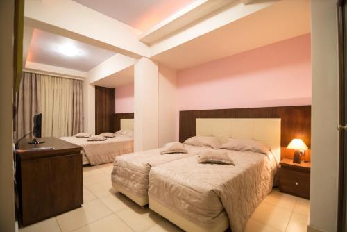 a bedroom with two beds and a desk at Panorama Hotel in Paralia Katerinis