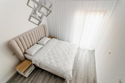 een witte slaapkamer met een bed en een raam bij Samplus Central Apartment in Craiova