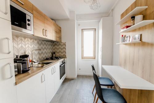 een keuken met witte kasten, een aanrecht en stoelen bij Samplus Central Apartment in Craiova
