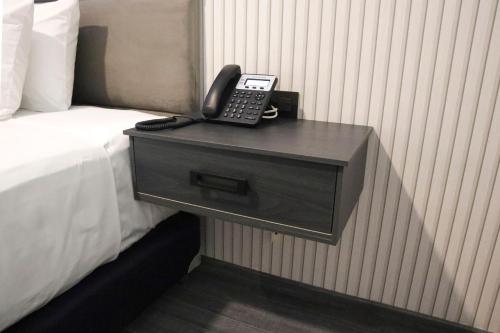 a phone on a night stand next to a bed at HUNICO HOTEL in Tulancingo