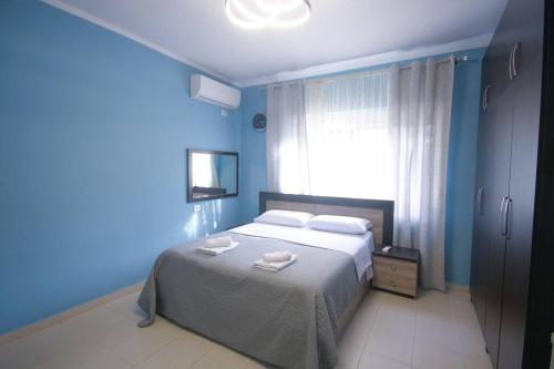 um quarto azul com uma cama com duas toalhas em Central 2BD Villa em Tirana