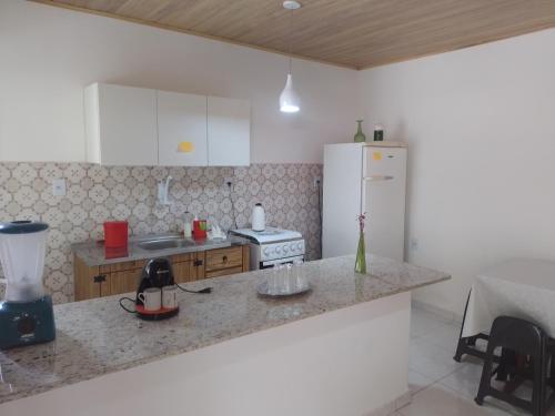 a kitchen with a counter and a white refrigerator at Casa Perto Praia do Forte in Cabo Frio