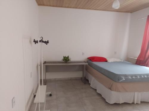 a small bedroom with a bed and a table at Casa Perto Praia do Forte in Cabo Frio