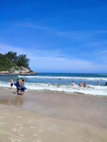 a group of people playing in the water at the beach at CASA DE PRAIA in Garopaba