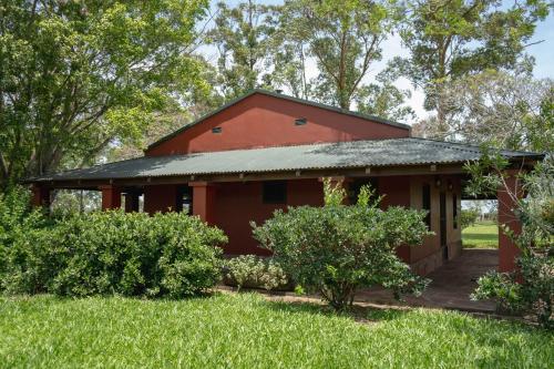 a red barn with a porch in a field at Estancia Iberá in Colonia Carlos Pellegrini