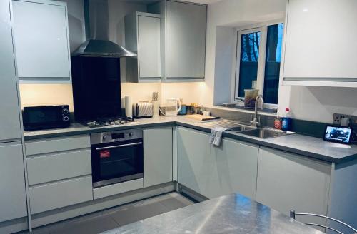 a kitchen with white cabinets and a stove top oven at Detached Boutique Luxury 3 Bed Villa Free Parking & WI-FI in Kingswood