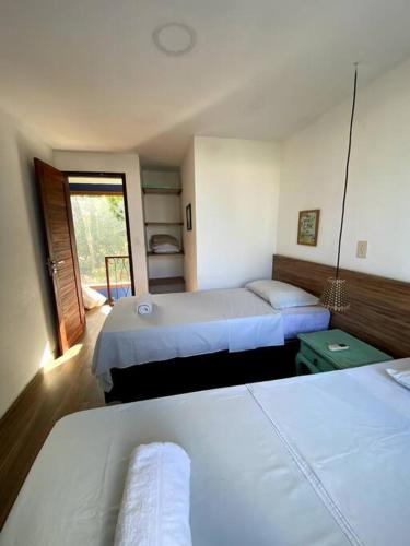 a hotel room with two beds and a window at Chalé Pipa Atlântico in Pipa