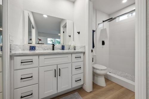 La salle de bains blanche est pourvue d'une douche et de toilettes. dans l'établissement Modern Dream Home - Fire Pit, Grill, Large Yard & AC, à Encinitas