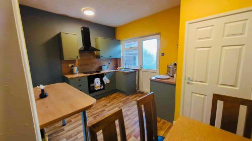 a kitchen with yellow walls and a wooden table at The Smart Stay - sleeps 5 Wigan central location in Wigan