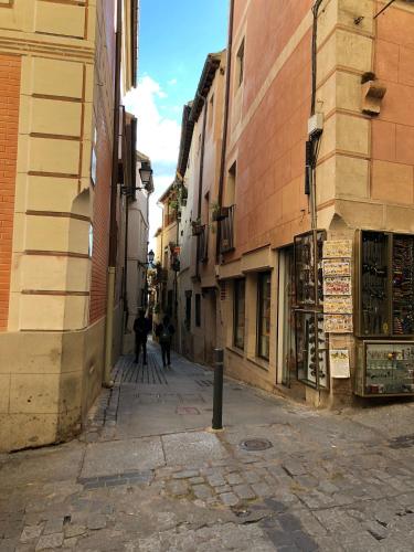 an alley with people walking down a street at Apart. Palacio Canónigo 7 - Junto Catedral in Toledo
