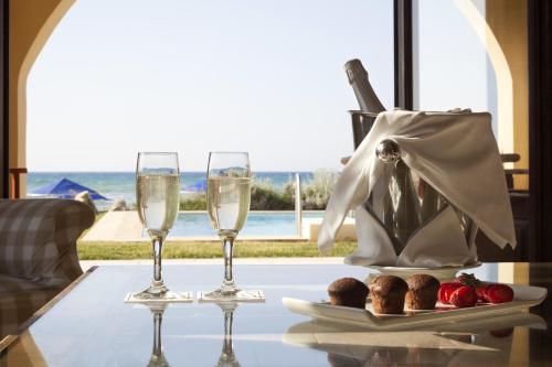 a table with a glass of wine and a plate of food at Aquila Rithymna Beach in Adelianos Kampos