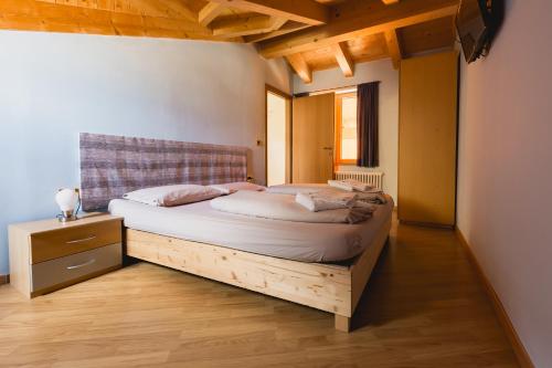 1 dormitorio con 1 cama grande en una habitación con suelo de madera en Bergreen Apartments, en Ossana