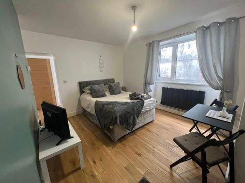a bedroom with a bed and a desk and a television at Dream Weaver Apartment in Swansea