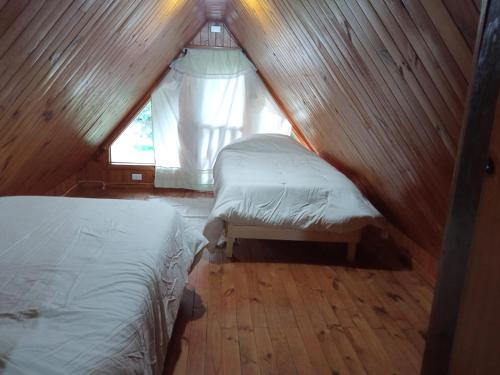 een slaapkamer op zolder met 2 bedden en een raam bij Las Bandurrias de Llifen in llifen