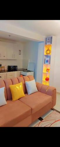 - un canapé brun avec des oreillers jaunes dans le salon dans l'établissement Triad apartments and Tsavo apartment, à Nairobi