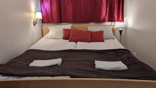 uma cama grande com almofadas vermelhas e brancas em Apartment Reki em Rovaniemi