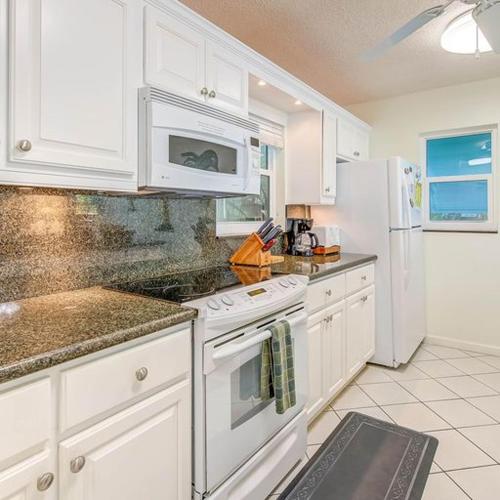 a kitchen with white cabinets and a white refrigerator at Little Bay Prime in Islamorada