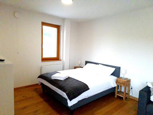 a bedroom with a bed with white sheets and a window at Studio Apartman 22, Rezidence Javor in Železná Ruda