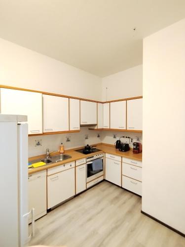 an empty kitchen with white cabinets and a sink at Schwert City Loft S41 in Verden