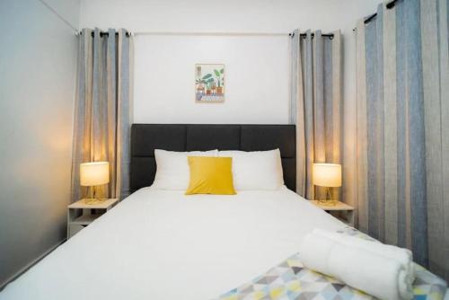 マニラにある3bd Lux City Oasis Las Pinasのベッドルーム(白い大型ベッド、ランプ2つ付)