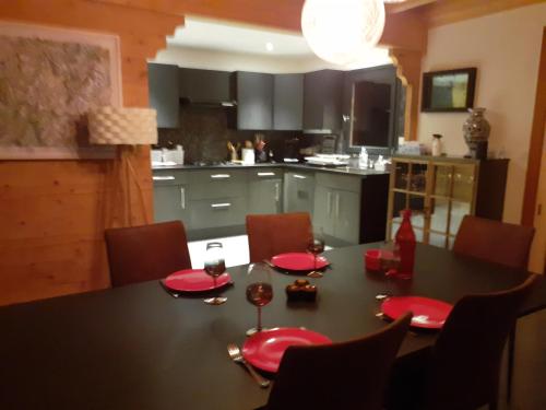a kitchen with a table with red plates and wine glasses at Charmant chalet 8p calme et vue sur montagnes in Verchères