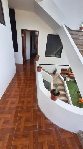 Galápagos Brunette Suites في بويرتو أيورا: درج في منزل مع أرضيات خشبية وتلفزيون