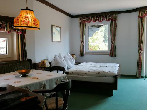 a bedroom with two beds and a table and a window at Hotel garni Landhaus Bürtlmair in Hinterstoder