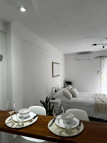 een slaapkamer met een bed en een tafel met wijnglazen bij Monoambiente temporario Centro La Plata in La Plata