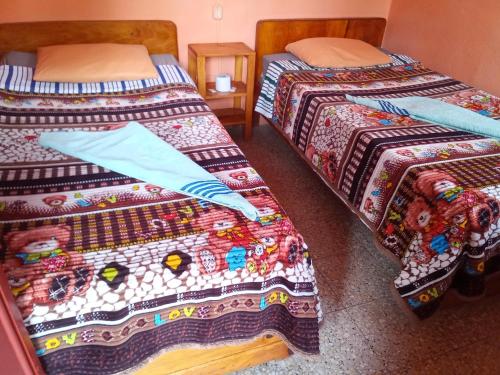 1 dormitorio con 2 camas y mantas coloridas en Hospedaje Santo Domingo en Panajachel