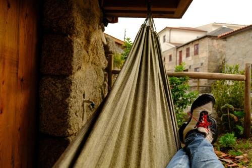 a person is sitting in a hammock at Refúgio House Natura Moinho de Água - Eco House in Guimarães