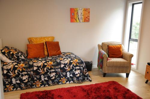 a living room with a bed and a chair at Nights on Broadway - The APARTMENT in Matamata