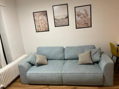 a blue couch in a living room with pictures on the wall at BRAN: Design - Apartment Küche, Parken ,Netflix in Bad Rothenfelde