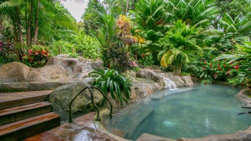 a pool in a tropical garden with a waterfall at Chachagua Rainforest Hotel & Hot Springs in Fortuna