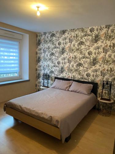 1 dormitorio con 1 cama grande y papel pintado con motivos florales en Appartement de kiki, en Éloyes