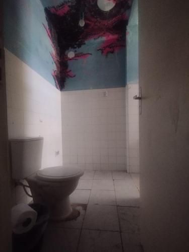 La salle de bains est pourvue de toilettes et d'une peinture murale. dans l'établissement Casa da Nanda, à Fortaleza