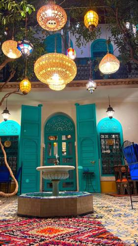 a room with blue doors and a table and chandeliers at Riad Al Nour in Marrakech