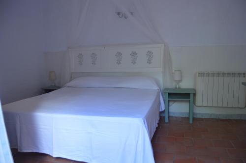 1 dormitorio con cama blanca y mesa auxiliar en El Campus, en Alaior