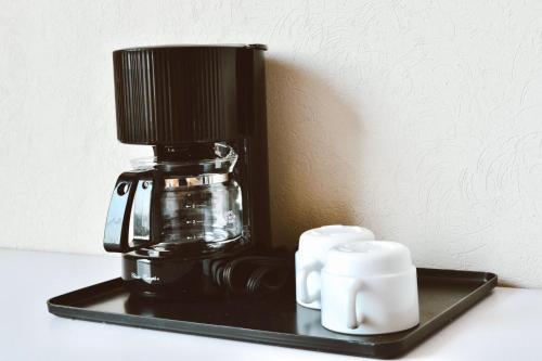 a black coffee maker on a black tray with two cups at HVH by Yaxché in Guadalajara