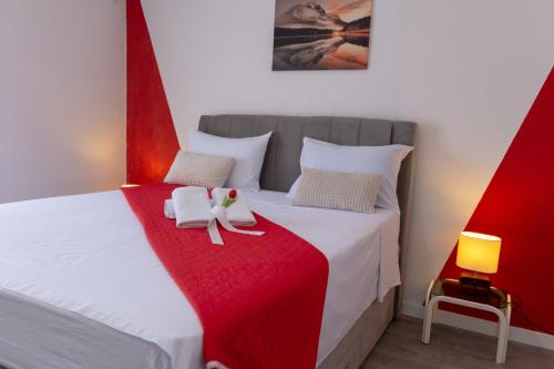 a bedroom with a white bed with a red blanket at Villa Blue Oasis in Kaštela