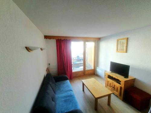 un salon avec un canapé bleu et une télévision dans l'établissement Le balcon d'Orcières, à Orcières