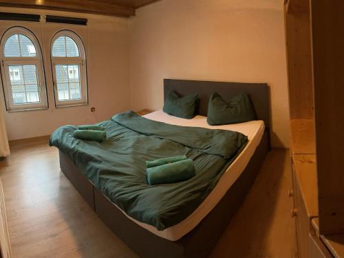 a bedroom with a bed with green sheets and pillows at Moderne Wohnung im Zentrum und Alte Wohnung im Zentrum in Eitorf