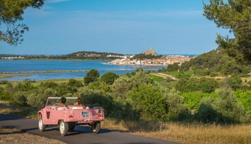 two people in a pink truck driving down a road at Villa Tamaris in Gruissan