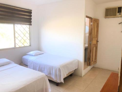 a bedroom with two beds and a window at Liza, habitación privada de Flor de Lis Beach House in Playas