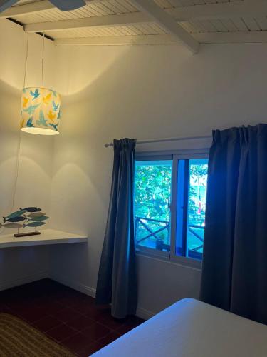 a bedroom with a bed and a window with blue curtains at Casa Grande Hotel Restaurant in Las Terrenas