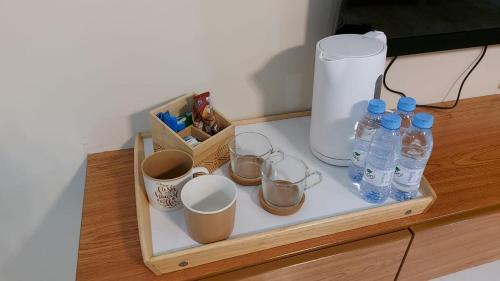 - un plateau avec des bouteilles d'eau et des tasses sur un comptoir dans l'établissement شقة مفروشة ليالي العروبة متميزة مؤثثة بأثاث أنيق ومريح, à Riyad