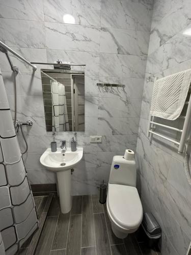 a white bathroom with a toilet and a sink at Modern Apartments Uzhgorod in Uzhhorod