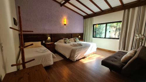 a hotel room with two beds and a couch at Sítio Costão da Fortaleza - Canyons do Brasil in Praia Grande