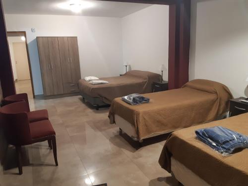 a hotel room with two beds and a chair at DEPARTAMENTO PLANTA BAJA in Villa Nueva