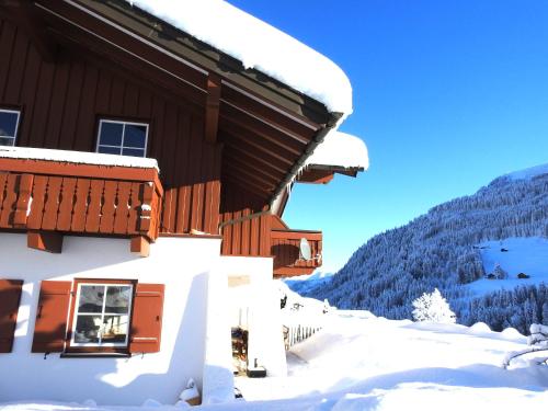 a building covered in snow with a mountain in the background at Haus Berg & Tal in Hirschegg