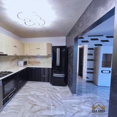 a kitchen with a marble floor and a black refrigerator at Vila Costi in Campina